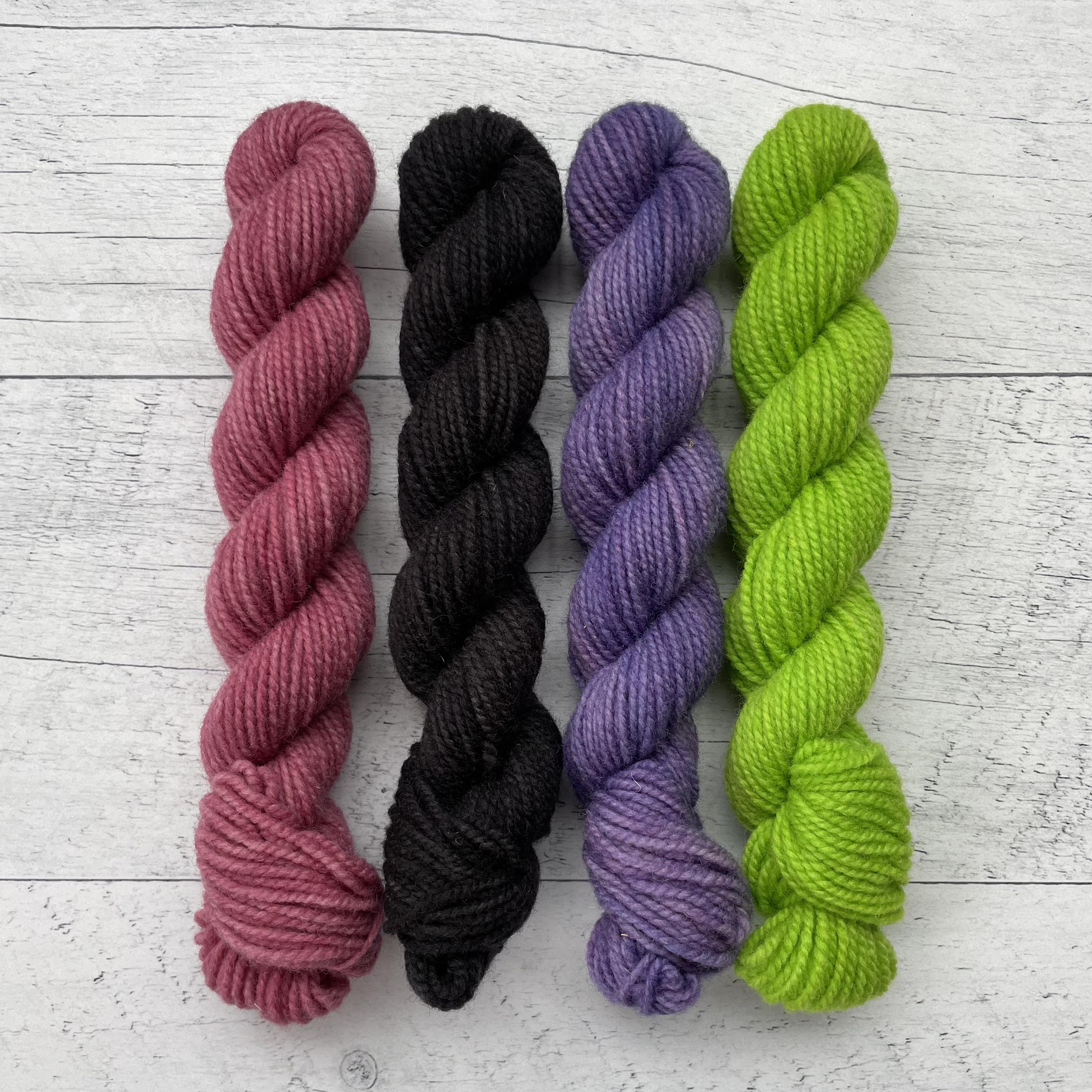 1 ensemble de 4 écheveaux de laine québecoise teinte à la main aux couleurs inspirées des années 90. De gauche à droite: fuchsia, noir, violet et vert néon